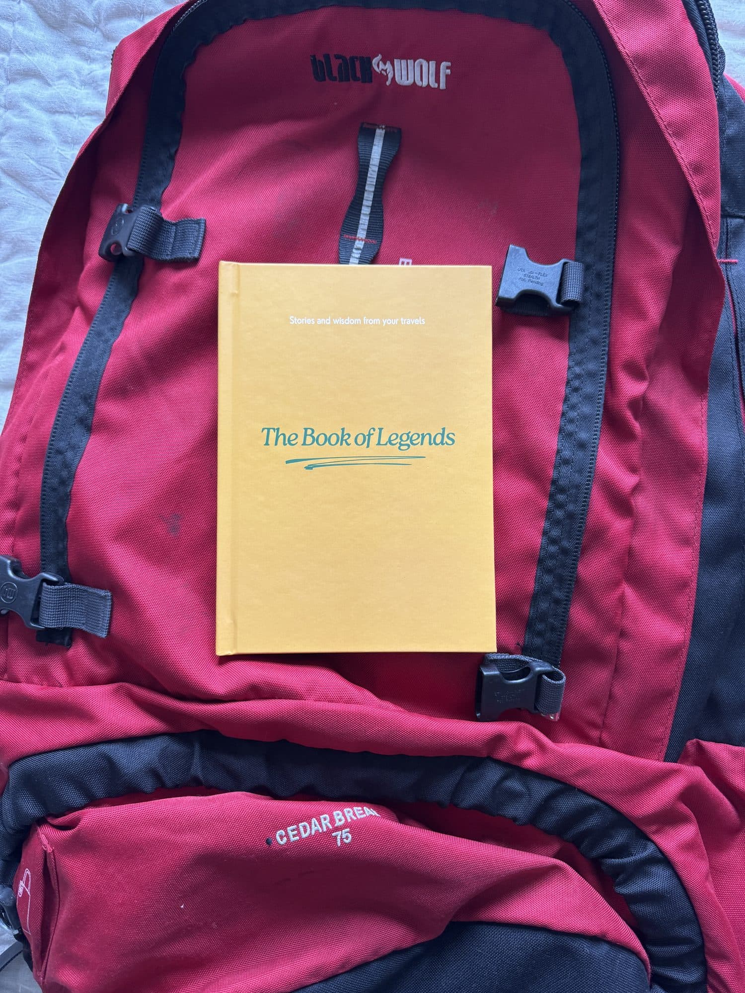 The Book of Legends strapped to the front of a red 75 litre backpack